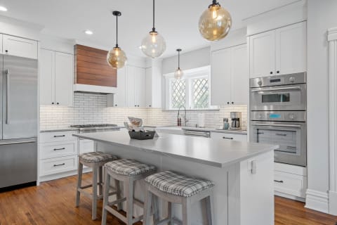 Modern kitchen with white cabinetry, gray countertops, and pendant lights.
