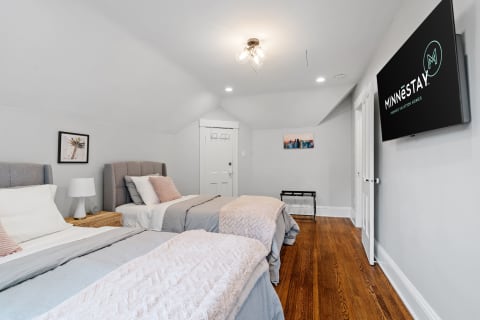 Cozy bedroom featuring twin beds, modern decor, and a 'Minnestay' branded television.