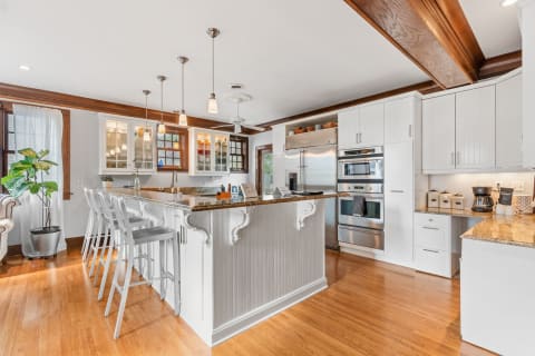 Modern kitchen featuring a granite island, stainless steel appliances, and white cabinetry.