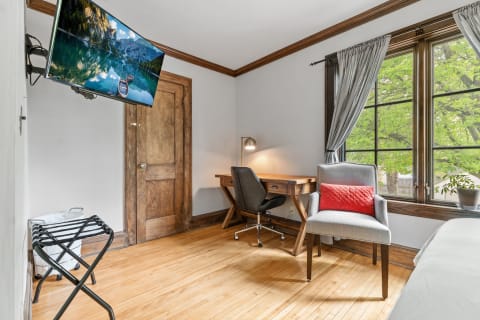 A cozy room with a desk and a window overlooking greenery.