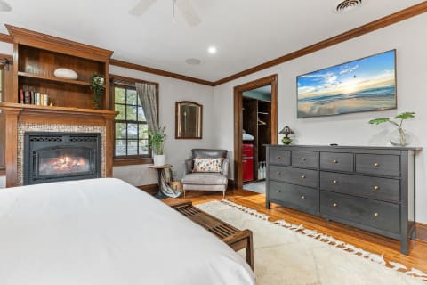 A warm and cozy bedroom with a fireplace, comfortable chair, and modern furnishings.