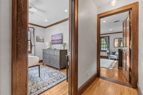 Interior view of a hallway leading to a bedroom with a gray dresser and living area.