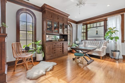 Interior of a cozy living room with a sofa, wooden furniture, and plants.