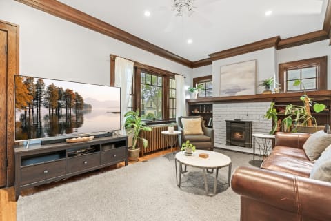 Warm living room with a TV showing nature scene, leather sofa, and modern fireplace.