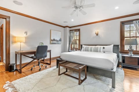A well-furnished bedroom featuring a bed, desk, and decorative elements.