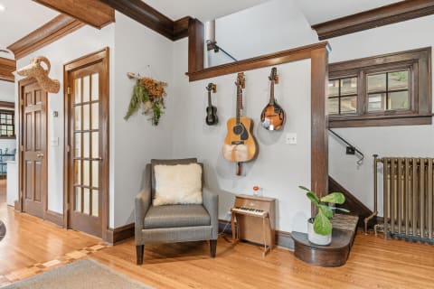 A corner of a room with musical instruments on the wall, an armchair, and a decorative plant.