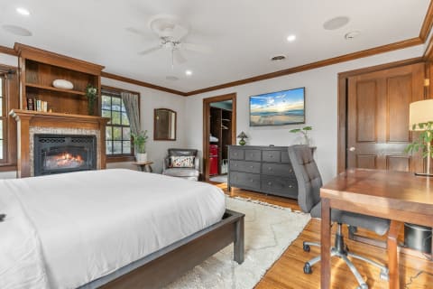Cozy bedroom with a fireplace, TV, and comfortable furnishings.
