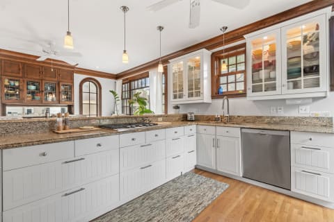 Modern kitchen with white cabinetry, granite countertops, and large windows.