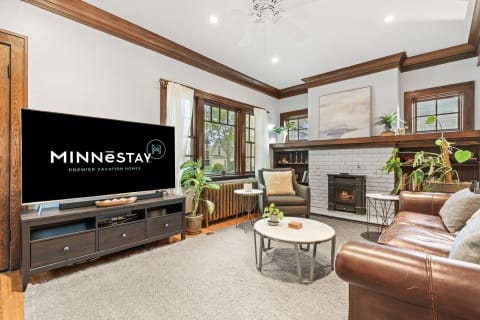 Inviting living room with a leather sofa, green plants, and a television featuring MINNESTAY logo.