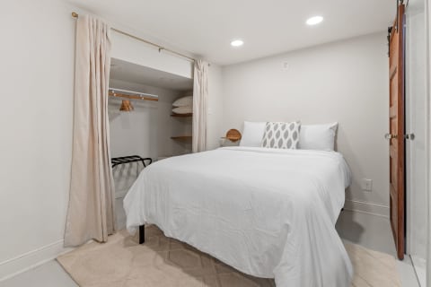 Cozy bedroom featuring a queen-sized bed, neutral decor, and a closet area.