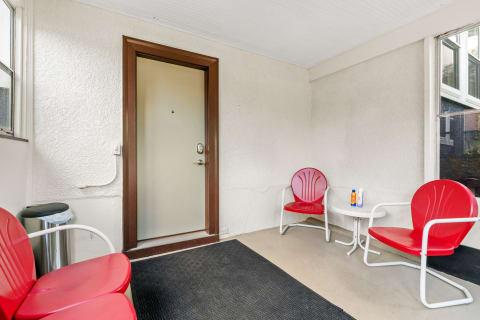A covered patio featuring red chairs and a door, ideal for relaxation.