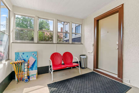 Enclosed porch featuring bright red chairs, large windows, and a display of sporting equipment.