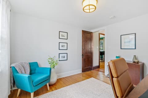 A bright living space with a turquoise chair and framed photographs on the wall.