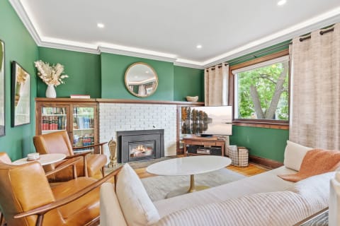 A stylish living room featuring green walls, a fireplace, and comfortable seating.