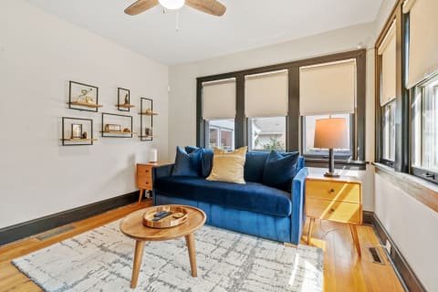 A well-lit living room featuring a navy sofa, decorative shelves, and a wooden coffee table.