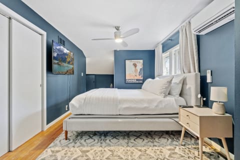 A stylish bedroom with blue walls, a plush bed, and a mounted television.