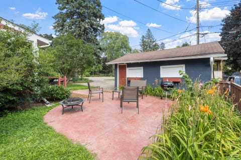 Private outdoor patio with chairs and a fire pit, surrounded by flowers and greenery
