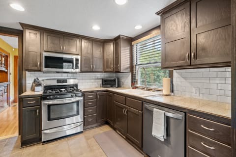 Modern kitchen with dark cabinets, stainless steel appliances, and granite countertops.