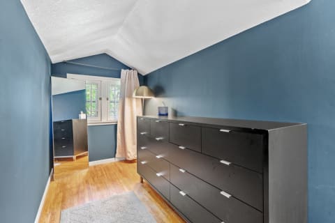 Interior view of a stylish bedroom corner with a black dresser, blue walls, and a full-length mirror.