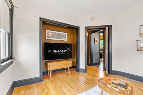 Cozy living room with hardwood floors, modern TV setup, and warm accent walls.