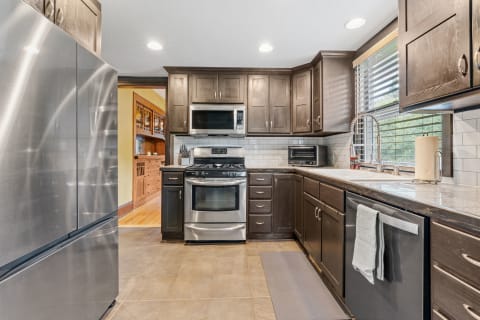 A sleek kitchen featuring stainless steel appliances, dark cabinetry, and granite countertops.