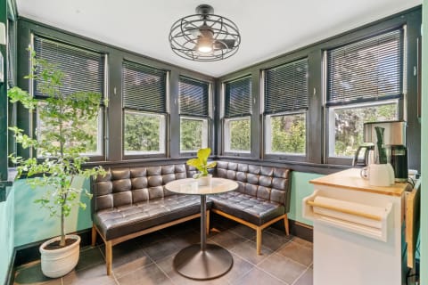 Cozy breakfast nook with leather banquette seating, corner windows, and a small round table.