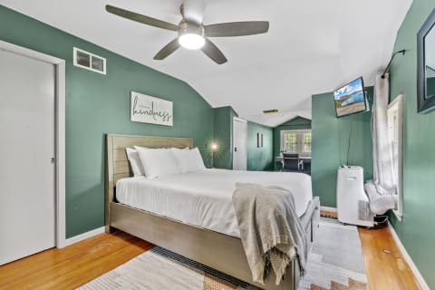 A serene bedroom with a green color scheme, modern fan, and cozy bedding.