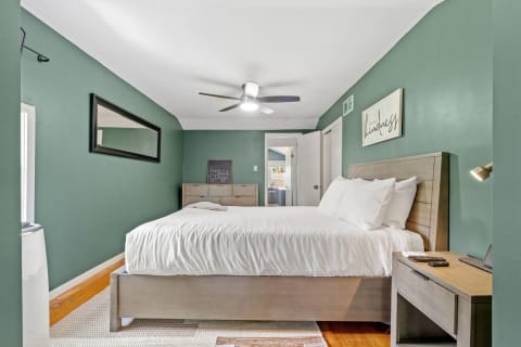 Serene bedroom with sage green walls and a comfortable bed framed by modern furnishings.