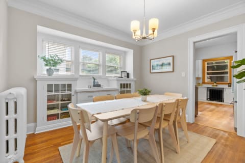 Bright dining room featuring a wooden table, minimalist chairs, and large windows.