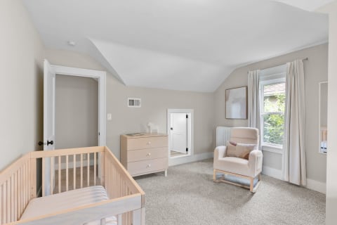 Cozy nursery with a crib, rocking chair, and dresser in soft tones.