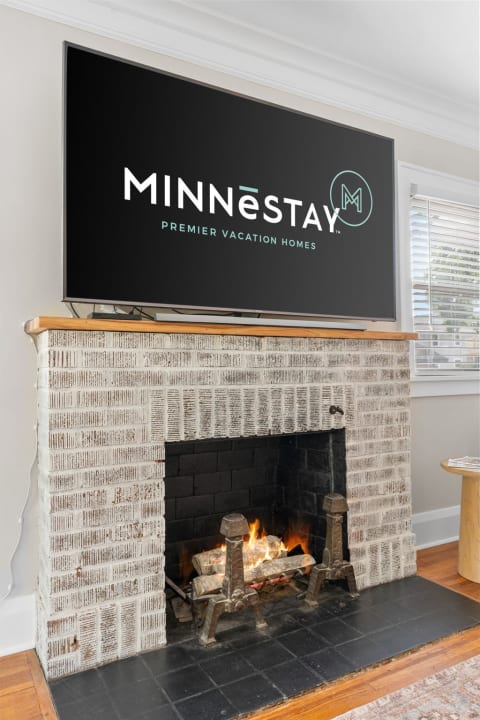 Living room featuring a fireplace with fire, above it is a TV showing the MINNESTAY logo.