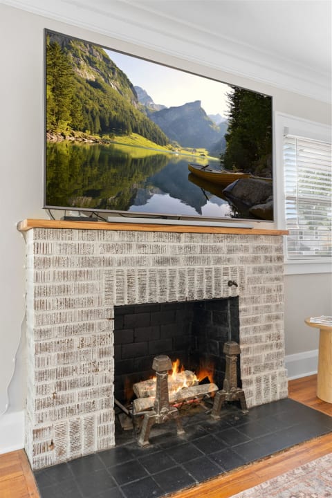 Living room with a fireplace and a TV displaying a serene mountain lake.