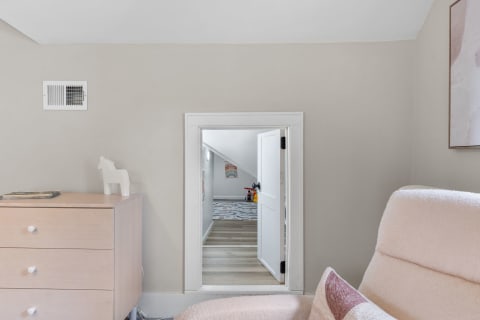 Interior view of a room with a dresser, a couch, and an open door leading to another area.