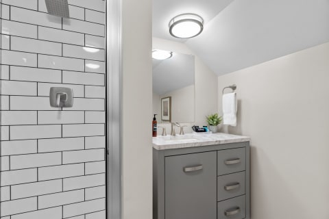 Modern bathroom with white subway tile shower and gray vanity.