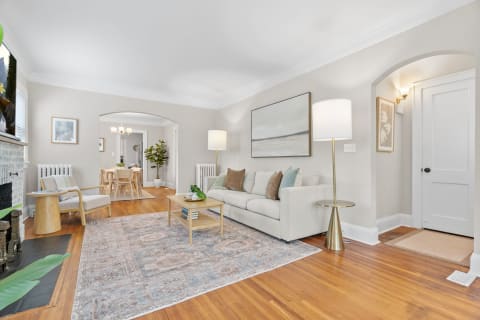 Cozy living room featuring a light-colored sofa, wooden chair, and warm lighting.