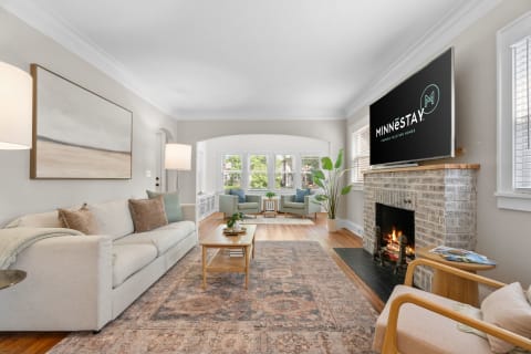 A beautifully decorated living room featuring a beige couch, a fireplace, and a mounted television.