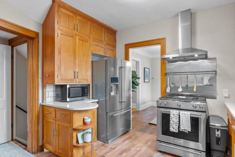 A spacious kitchen featuring wooden cabinets, a stainless steel refrigerator, and a gas range.