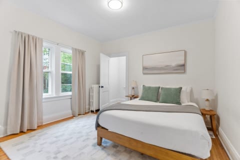 Cozy bedroom with bed, soft pillows, and warm lighting.
