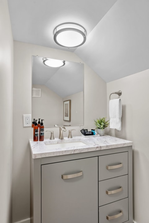 Modern bathroom with a marble countertop vanity and light fixtures.