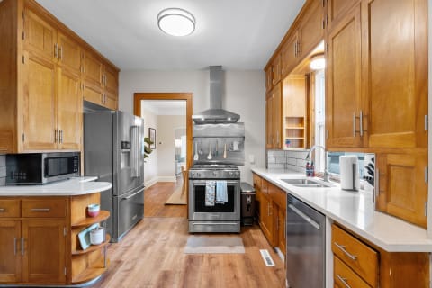 Interior view of a modern kitchen featuring wooden cabinets, stainless steel appliances, and natural light.