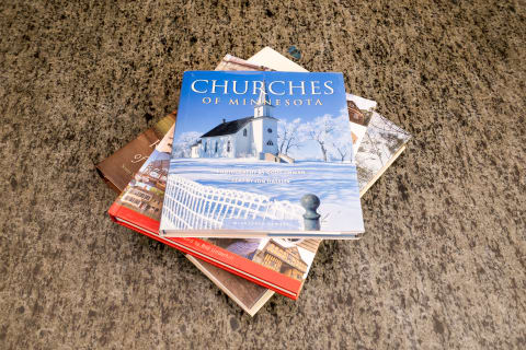 Stack of books on a stone surface, with 'Churches of Minnesota' on top.