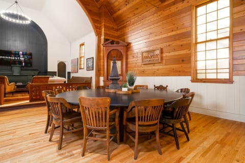 A warmly decorated gathering space featuring a round table, wooden chairs, and a cozy atmosphere.
