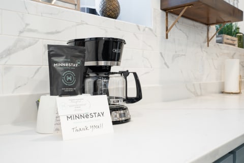 Sleek black coffee maker with a bag of coffee and a thank-you card on a modern kitchen countertop.