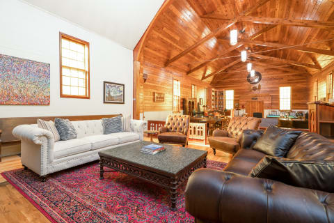 Spacious living room featuring wooden beams, plush sofas, and artistic decor.
