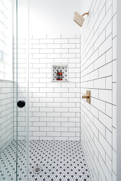 Contemporary shower area with white tiles and black hexagonal floor.