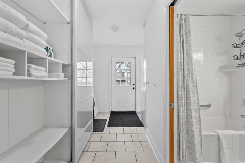 An inviting bathroom entrance with white towels, a mirror, and a view of a bathtub.