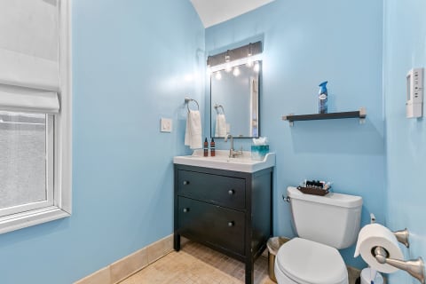 A modern powder room featuring blue walls, a stylish vanity, and a clean aesthetic.