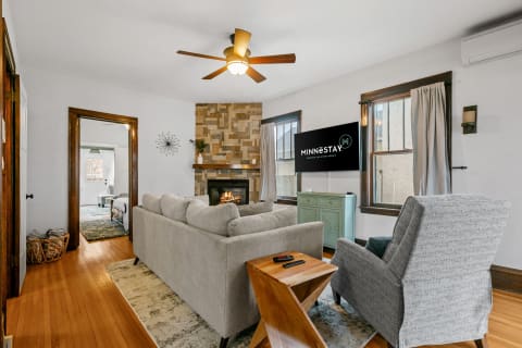 A cozy living room featuring a gray sectional sofa, a stone fireplace, and a flat-screen TV.