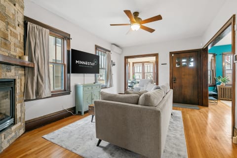 A cozy living room with a gray sofa, stone fireplace, and modern amenities.