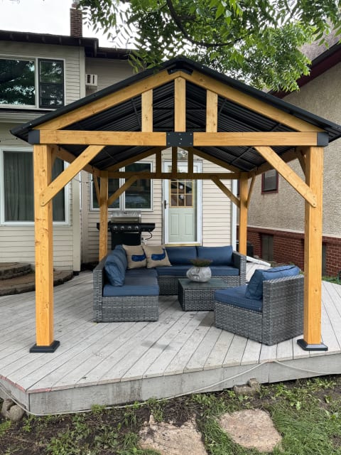 Outdoor seating area with a gazebo, featuring wicker furniture and blue cushions.